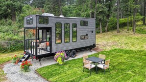 Un camping-car Timberwolf doté d’un porche couvert, d’une petite terrasse avec une table et des chaises, et d’une allée en gravier.