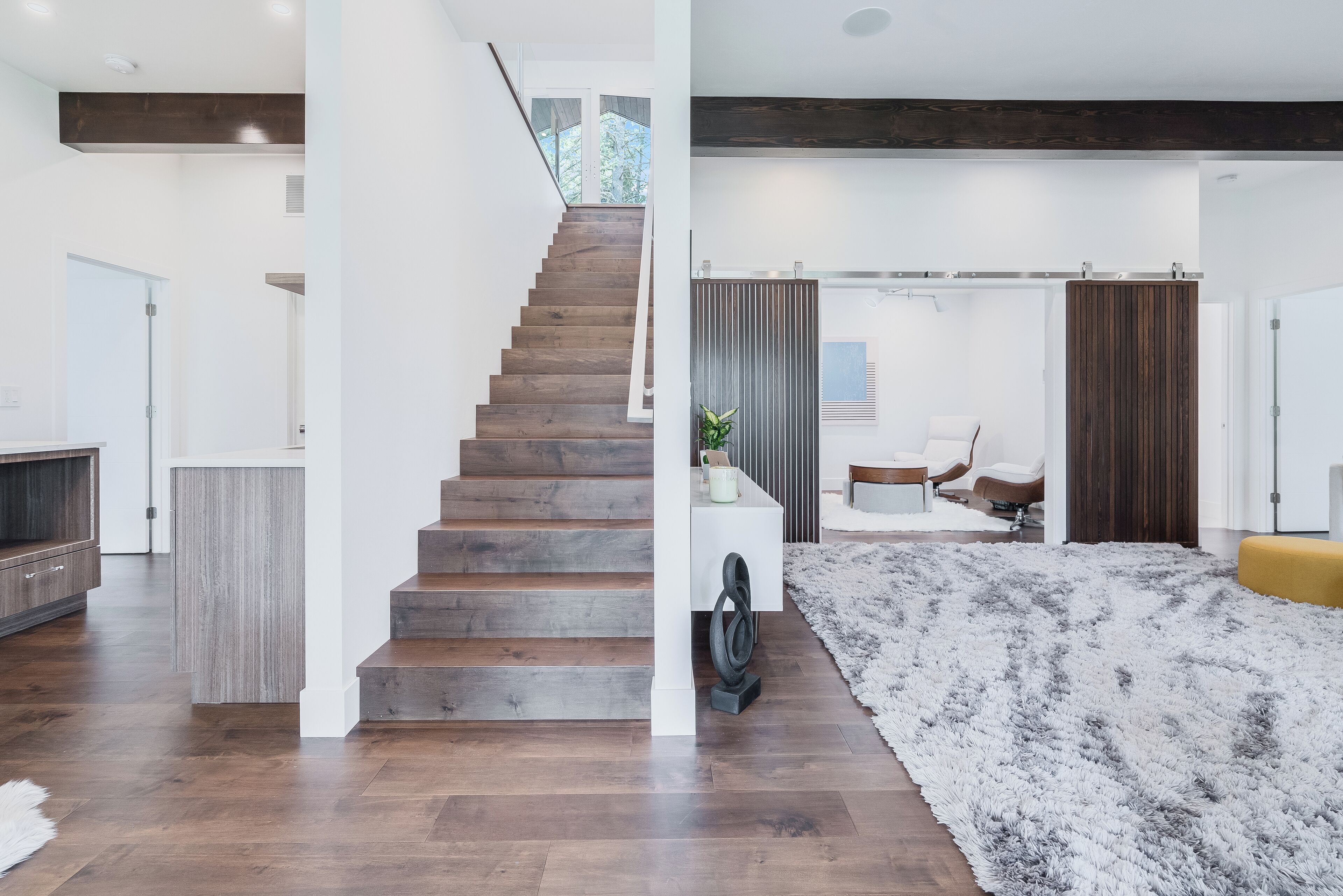 Ein modernes Interieur mit einer Holztreppe, einem weißen Sofa und einem flauschigen Teppich.