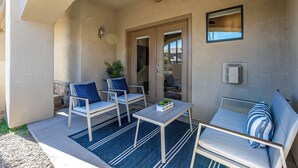 Eine überdachte Terrasse mit Deckenventilator, zwei Stühlen, einem Tisch und einer Couch.