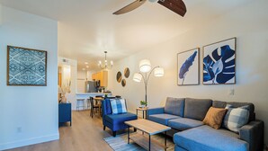 Ein modernes Wohnzimmer mit einem grauen Sofa, einem Couchtisch und einem Essbereich im Hintergrund.