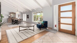 Amplia sala de estar con comedor, una puerta grande de madera y vistas al exterior.