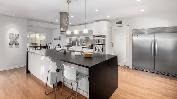 Una cocina moderna con una isla central, electrodomésticos de acero inoxidable e iluminación colgante.
