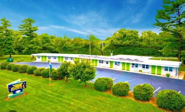 A motel with a green and white exterior, a parking lot, and a well-maintained lawn. - The Springs Motel (Yellow Springs)