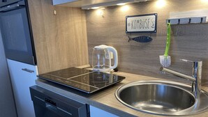 Eine moderne Küche mit integriertem Induktionskochfeld, einer Edelstahl-Spüle und einem Wasserkocher.