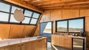 A modern kitchen with wooden cabinetry, a large island, and a view of the desert through large windows.