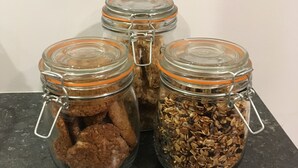 Quatre bocaux en verre munis de fermoirs métalliques, posés sur un plan de travail sombre.