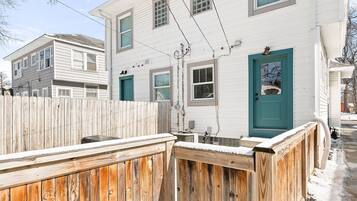 A two-story house with a wooden fence and a teal door.