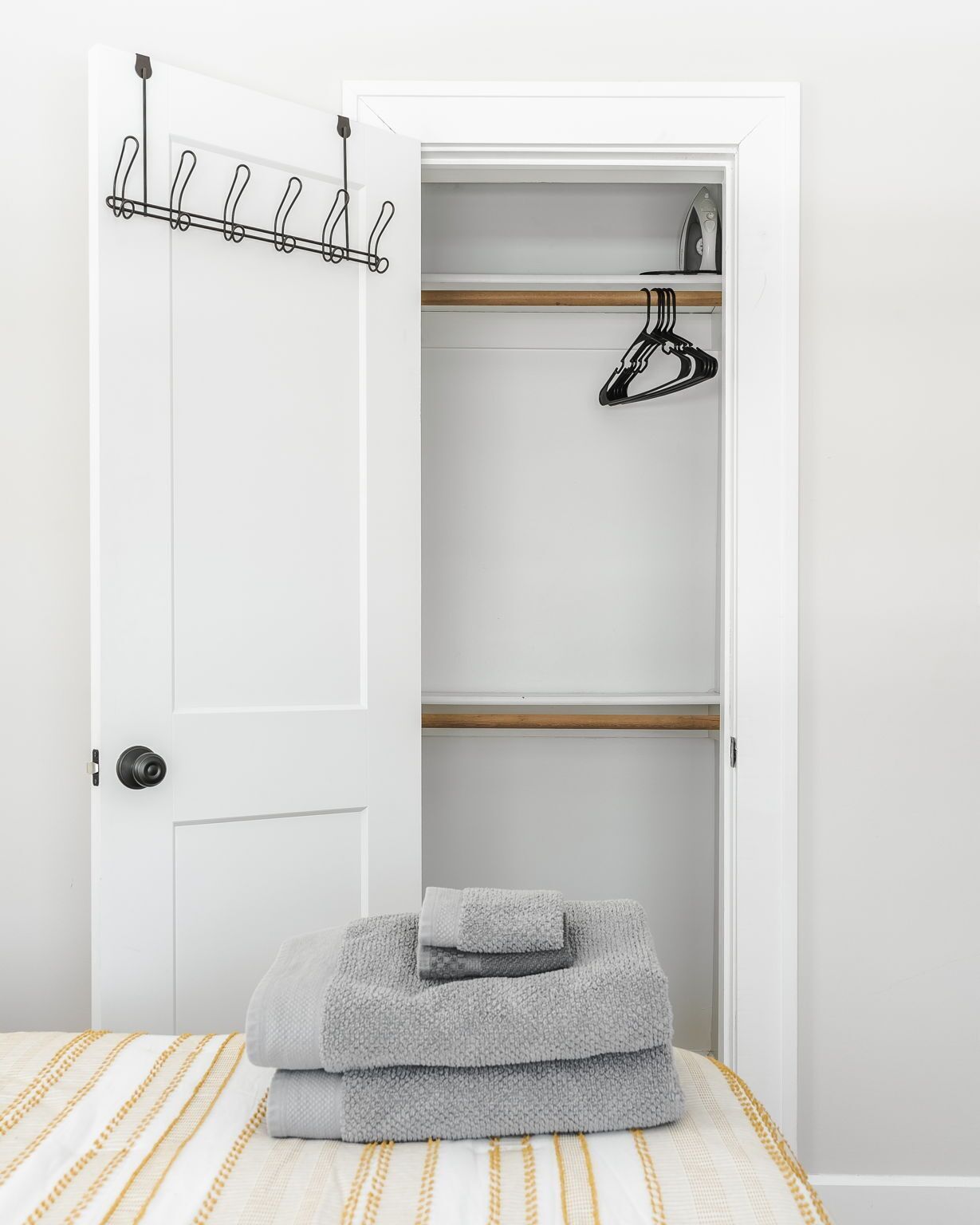 A bedroom with a bed, a closet with hanging space, and a folded towel on the bed.