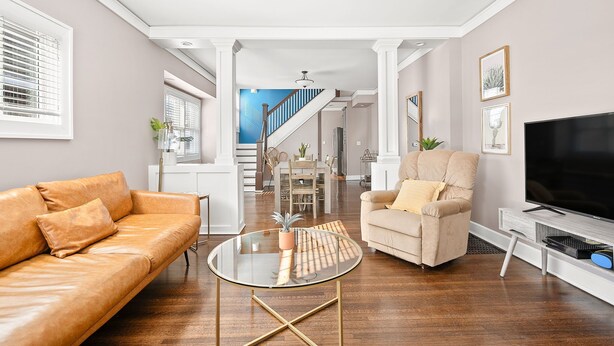 A modern living room with a leather sofa, a glass coffee table, a beige armchair, and a flat-screen TV. - Adorable Broad Ripple Duplex (Indianapolis)