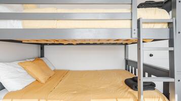 A bunk bed with a ladder, a bed with a yellow bedspread, and a white pillow.