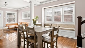 A dining area with a wooden table and chairs, a bench, and a potted plant. - Adorable Broad Ripple Duplex (Indianapolis)