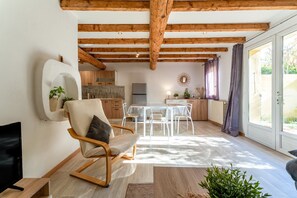 A spacious living area with a wooden ceiling, a dining table, and a TV. - Holiday Home 'Maisonnette' with Private Terrace, Garden and Wi-Fi (Le Thor)