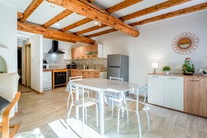 A modern kitchen with wooden beams, a dining table with chairs, and a refrigerator. - Holiday Home 'Maisonnette' with Private Terrace, Garden and Wi-Fi (Le Thor)