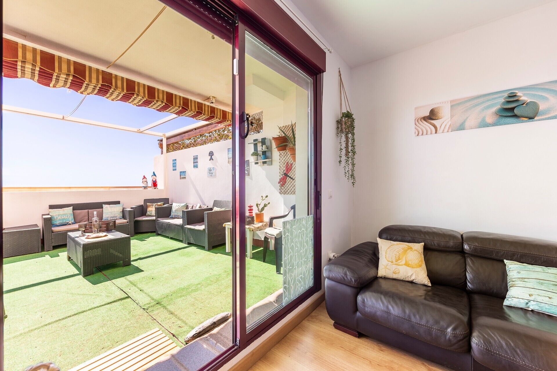A living room with a view of a patio area, a sliding glass door, and a painting on the wall.
