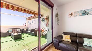 A living room with a view of a patio area, a sliding glass door, and a painting on the wall.