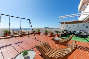 A terrace with a swing set, seating area, and potted plants.