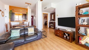 Un salon comprenant un canapé, un téléviseur, un meuble en bois et un ventilateur de plafond.