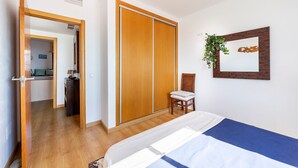 Une chambre à coucher avec un lit, une armoire en bois, une chaise, un miroir et une plante.