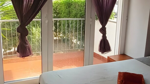 Ein Schlafzimmer mit Bett, Vorhängen und Blick ins Freie.