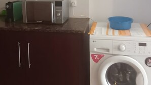 Eine Küche mit dunklen Schränken, einer Mikrowelle und einer Waschmaschine mit Frontlader.