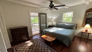 Ein Schlafzimmer mit einem Bett, einem Deckenventilator, einem Nachttisch, einer Lampe, einer Kommode und einem Fenster.