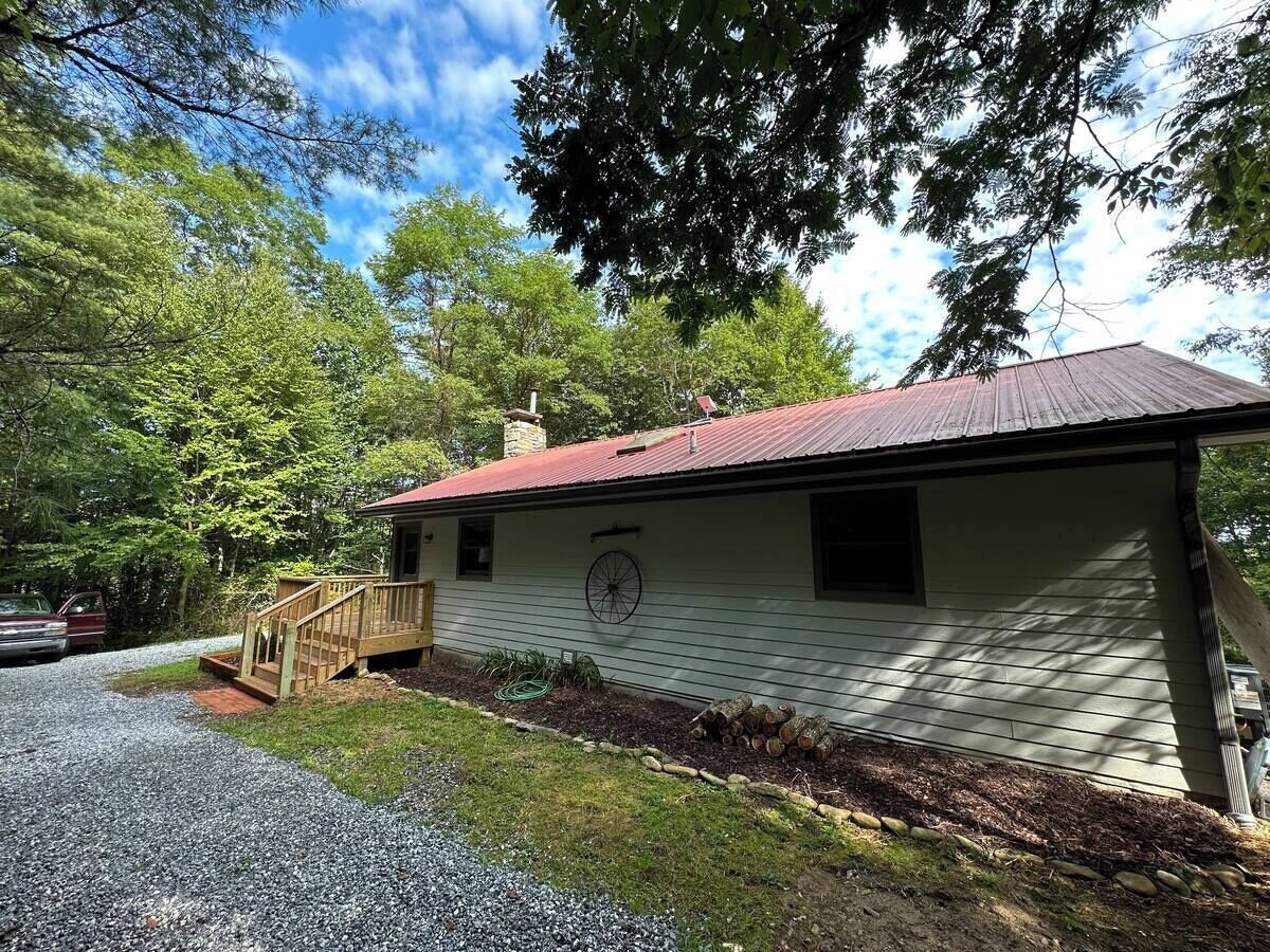 A single-story house with a red roof, a wooden deck, and a gravel driveway.