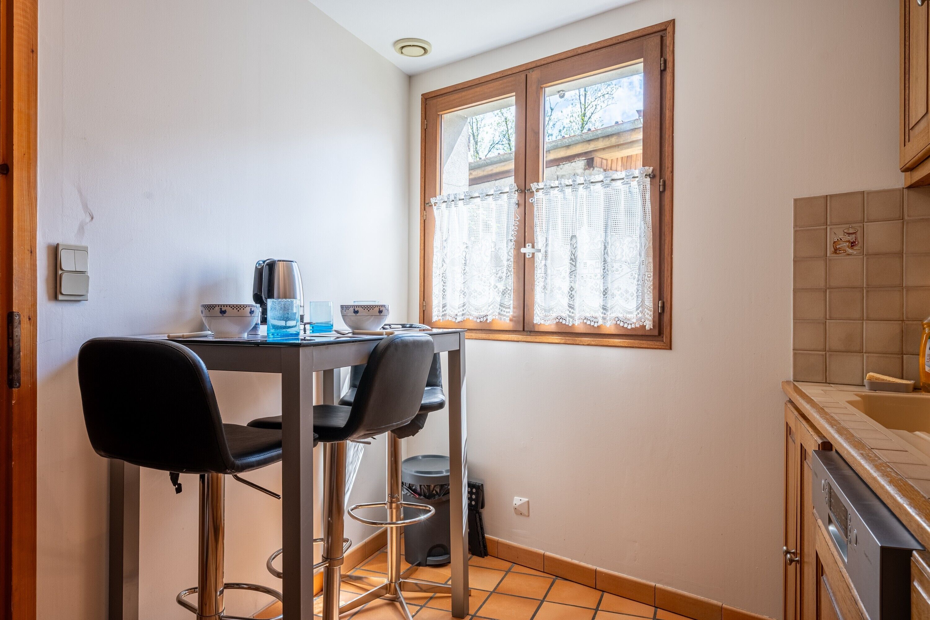 Une petite cuisine avec une fenêtre, une table et des chaises, et un évier.