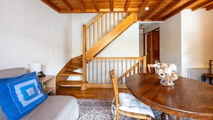A wooden staircase, a dining table with a decorative bowl, and a bed with a blue pillow. - Cottage 'Marie Andre' with Private Terrace and Wi-Fi (Entrelacs)