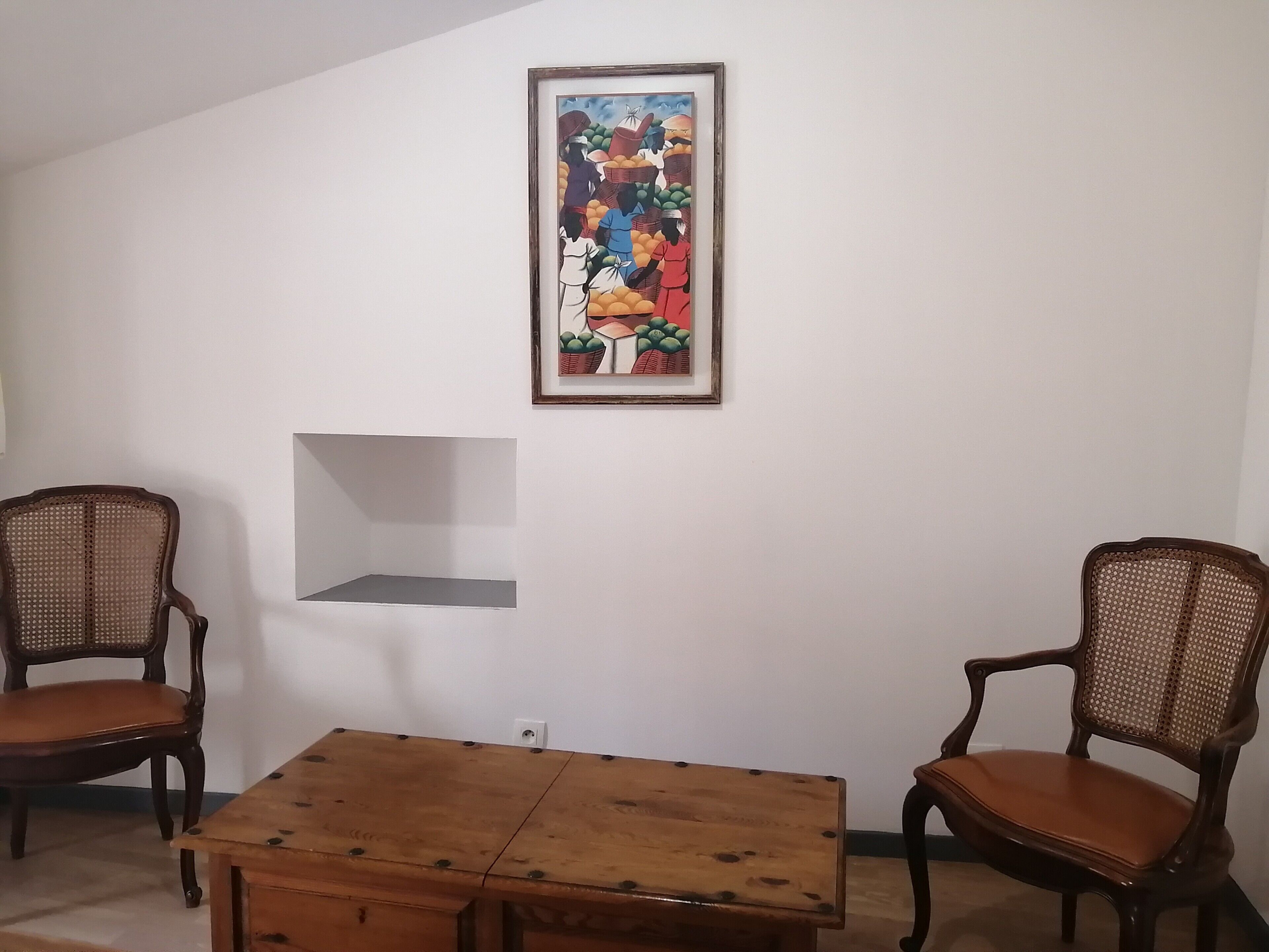 A dining area with a wooden table and two wicker chairs.