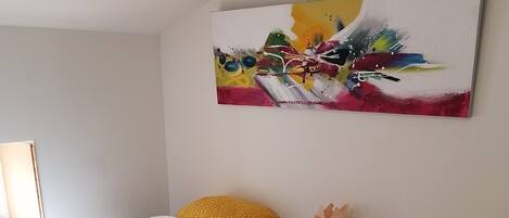 Ein Hotelzimmer mit zwei Betten, jedes mit einer weißen, gesteppten Bettdecke und einem gelb gepunkteten Kissen. Darüber an der Wand hängt ein Gemälde.