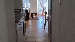 Ein schmaler Flur mit einer Waschmaschine, einem kleinen Tisch und einem Stuhl.