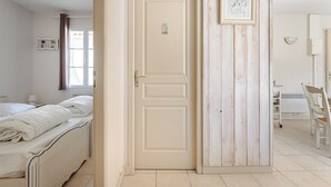 Une chambre à coucher avec un lit, une porte, une étagère fixée au mur et une chaise.