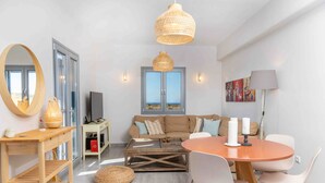 En moderne stue med sofa, sofabord, spisebord og et stort spejl.