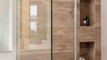 Une salle de bain moderne avec une douche à parois de verre, un lavabo blanc et des étagères intégrées pour le rangement.