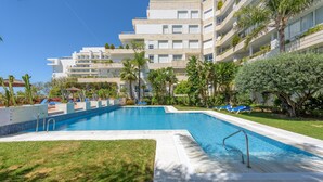 A swimming pool with a clear blue water, surrounded by a well-maintained lawn and palm trees. - Apartment 'Del Mar' with Sea View, Wi-Fi and Air Conditioning (Marbella)