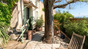 A rustic stone building with a tree in front, steps leading to a door, and a bench. - Holiday Home 'Le Sophora' with Mountain View, Wi-Fi and Air Conditioning (ROCHEFORT DU GARD)