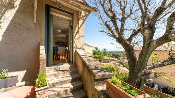 A stone building with a staircase leading to an open door, a tree, and a view of a landscape. - Holiday Home 'Le Sophora' with Mountain View, Wi-Fi and Air Conditioning (ROCHEFORT DU GARD)
