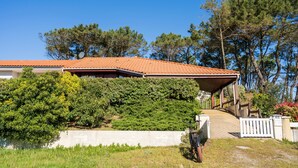 Ein Haus mit rotem Ziegeldach, einer Veranda und einem weißen Zaun.