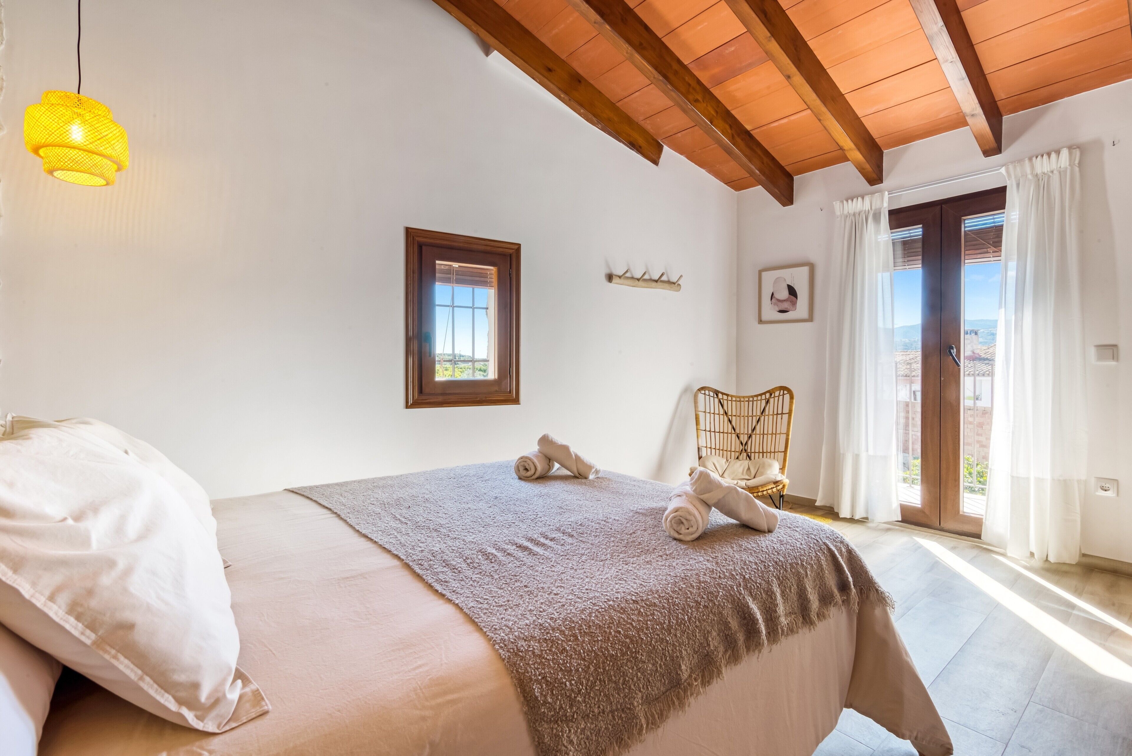 A bedroom with a bed, a window, a chair, and a view of the outside.