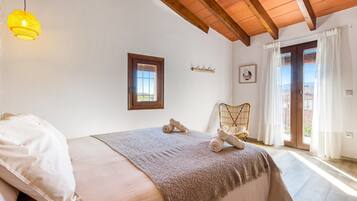 A bedroom with a bed, a window, a chair, and a view of the outside.
