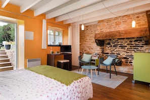 A bedroom with a bed, a desk, a chair, a stone wall, and a fireplace. - Guest Room 'Magnolia' with Shared Pool, Shared Terrace, and Wi-Fi (Arzano)