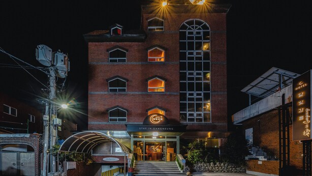 Ein Hotel mit Backsteinfassade, großen Bogenfenstern und einem Schild, das es als Hotel kennzeichnet.