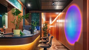 Eine moderne Hotelhalle mit einer Rezeption, einer Sitzecke und einer großen, beleuchteten Wandgestaltung.