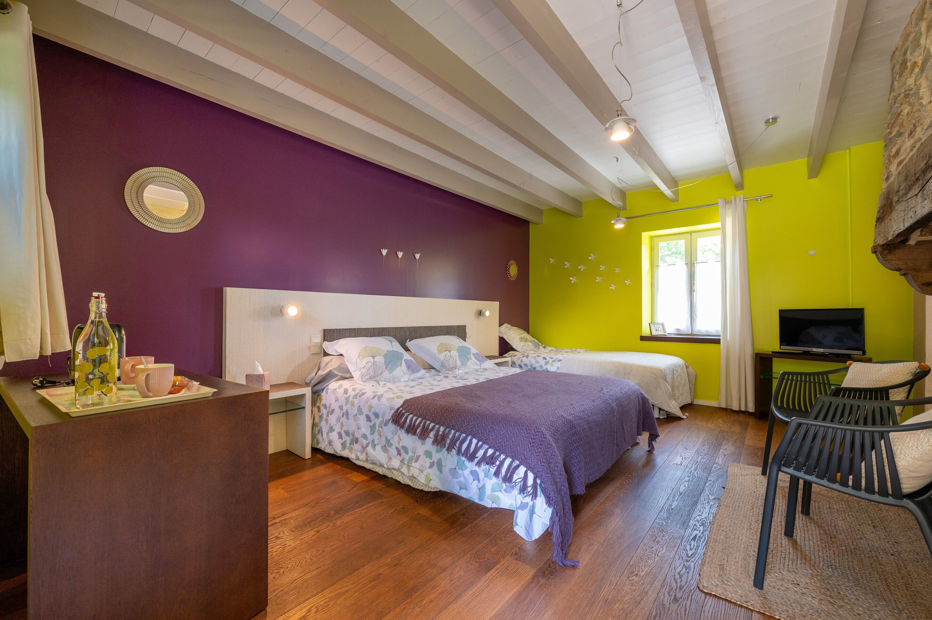 Una habitació amb dos llits, una taula de treball, televisió i una finestra amb cortines.