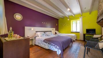 Una habitació amb dos llits, una taula de treball, televisió i una finestra amb cortines.