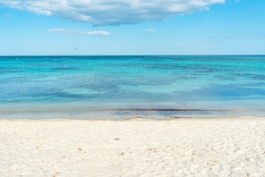Ein Strand mit klarem türkisblauem Wasser und weißem Sand.