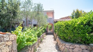 Un sendero de piedra que conduce a un edificio con tejado de baldosas, rodeado de vegetación.