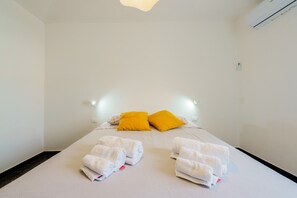 Habitación de hotel con cama, dos almohadas, aire acondicionado de pared y lámpara de noche.