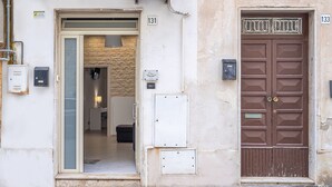 A building entrance with a glass door, a brown double door, and numbered signs '131' and '133'. - Apartment 'Dafne Home' with Wi-Fi and Air Conditioning (Siracusa)