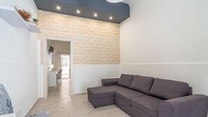 A modern living room with a sectional sofa, a small table, and a chair. - Apartment 'Dafne Home' with Wi-Fi and Air Conditioning (Siracusa)